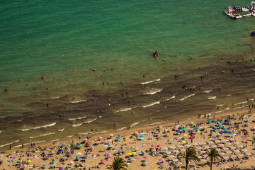 Crowded beach with a blue Mediterranean sea seen from a hill