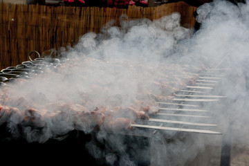 Barbecue skewers meat kebabs on flaming grill. Smoke coming from a hot barbecue fire.