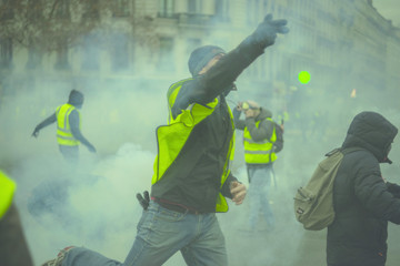 Manifestants renvoyant des grenades lacrymogènes durant une manifestation. - obrazy, fototapety, plakaty