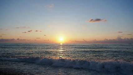 Beautiful sunset on Pebble beach and sea. Waves attack the stony beach.