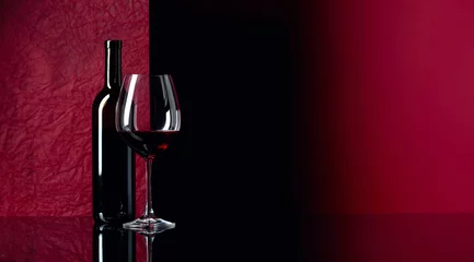 Wandaufkleber Flasche und Glas Rotwein auf einem schwarzen Tisch. © Igor Normann