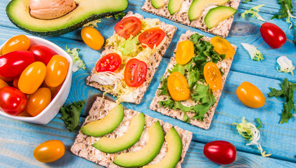 Healthy snack from wholegrain rye crispbread cracker with cherry tomatoes, avocado and salad. Proper nutrition. - 283344010