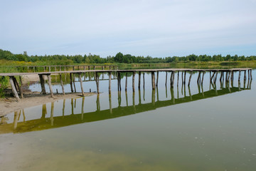 Fototapeta na wymiar Two empty wooden old bridges on a lake in drought in Ukraine. Bridges of handicraft work.