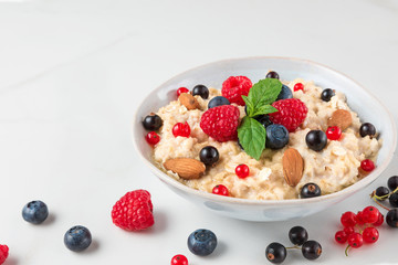 healthy homemade oatmeal porridge with berries, nuts and mint. diet breakfast food concept