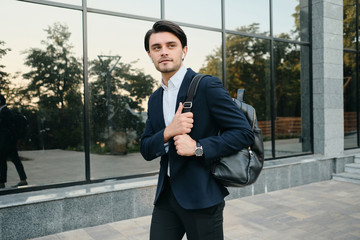 Young beautiful bearded brunette man in white shirt and classic suit with wireless earphones and...