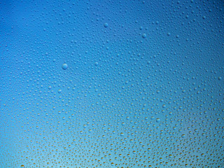 Water droplets on the glass with a colored background. Drops of water.