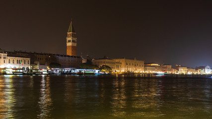 Fototapeta na wymiar Bell tower and historical buildings at night at Piazza San Marco from the Basilica di Santa Maria della Salute in Venice, Italy.