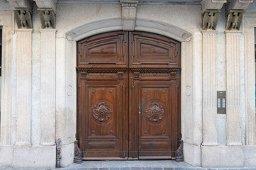 Fototapeta na wymiar affascinante antica porta in legno ingresso palazzo con ornamenti aquile di pietra italia