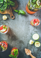 Homemade fresh strawberry and basil lemonade or iced- tea in glass tumblers with eco-friendly plastic-free straws and fresh ingredients over dark grey table background, top view, copy space