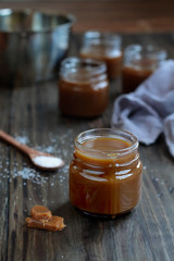 Little jars of salted caramel sauce over a rustic table. Selective focus with blurred background.