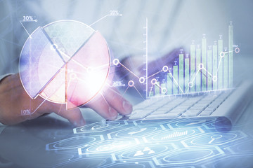 Double exposure of graph with man typing on computer in office on background. Concept of hard work.