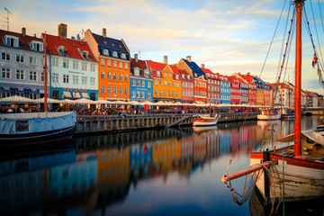 Nyhavn Harbour at sunset in Copenhagen Denmark with colorful houses reflection and a boat