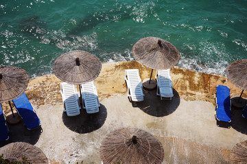 beach umbrellas and chairs against the blue sea on the beach of Albania. A popular tourist resort on the Ionian Sea.