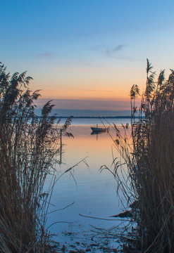blue hour in summer time by a lake with a small boat in between the reeds
