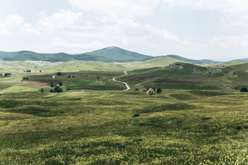Obraz premium Beautiful view of the natural landscape in Montenegro with a field and authentic houses with a mountain in the background.