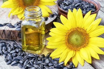 Sunflowers and seeds on a wooden background near sunflower oil in a glass jar. Healthy foods and...