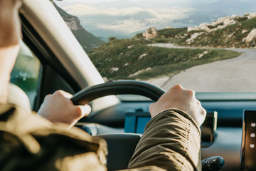 Close-up. The driver's hand on the steering wheel. The driver or traveler or tourist is driving a car.