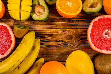 Still life with exotic fruits. Bananas, mango, oranges, avocado, grapefruit and kiwi fruits on wooden table. Top view