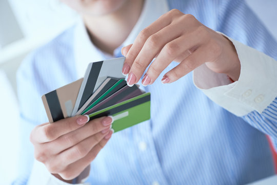 Woman hand holding various credit cards and making choice with another hand close-up.