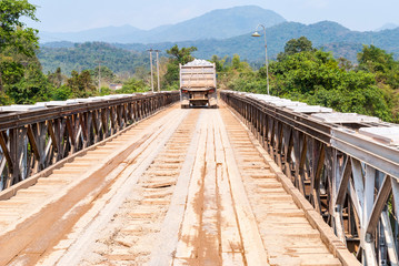 Truck driving over wooden bridge, Laos