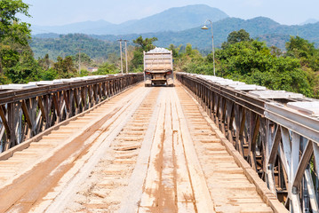 Fototapeta premium Truck driving over wooden bridge, Laos