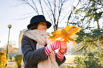 Autumn outdoor portrait of girl with yellow maple leaves