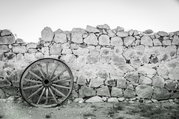 Fototapeta na wymiar Rustic wagon wheel and stone wall