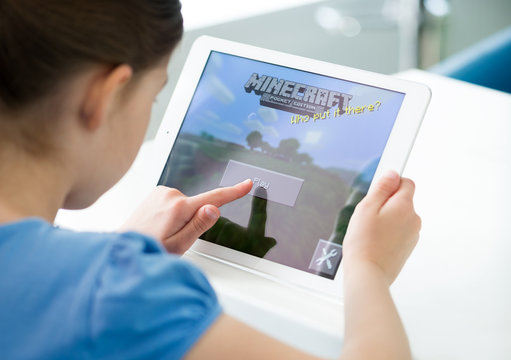 KIEV, UKRAINE - MAY 21, 2014: A girl starts playing Minecraft game on an Apple iPad Air digital tablet. 