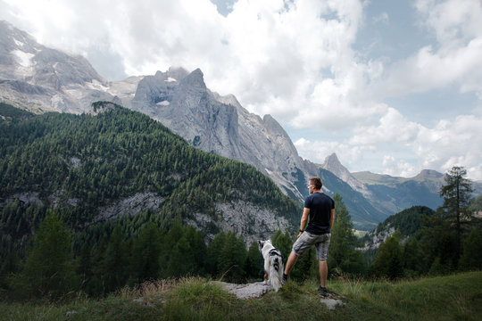 Dog With A Man In The Mountains At Sunrise. Travel With A Pet.