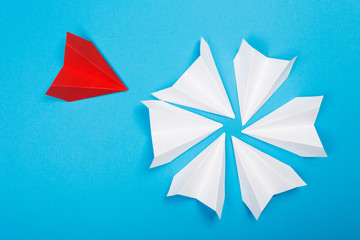 Group of white paper plane in one direction and one red paper plane pointing in different way on blue background. Business for innovative