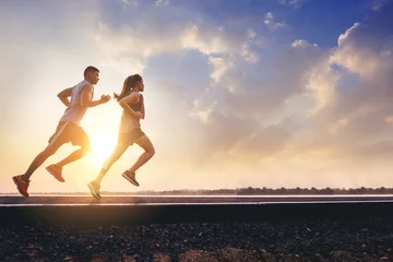 Poster Jonge paren die sprinten op de weg lopen. Fit runner fitness runner tijdens buitentraining met zonsondergang achtergrond © Panumas