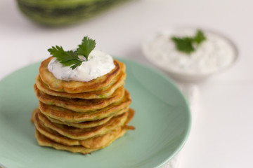 fresh delicious zucchini pancakes with sour cream and herbs on the table