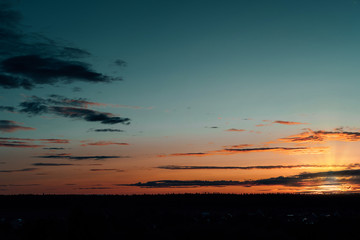 Evening sky at sunset background. Dark clouds hanging above horizon. Majestic cloudscape in blue, orange, violet shades. Grey cloudlets bringing rain. Countryside skyline in twilight time