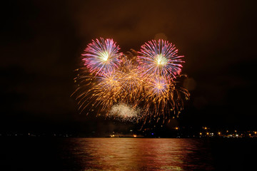 Beautiful colorful fireworks in sky over river. Big festive evening event with great pyrotechnic show.  