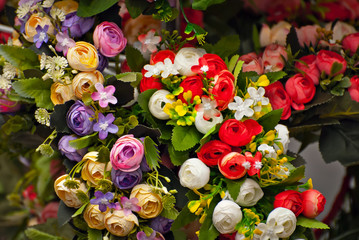 Bouquets of artificial flowers are sold at the fair. Corollas of colored small flowers. Closeup of...