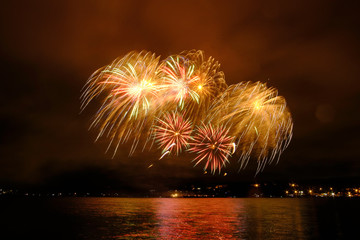 Beautiful colorful fireworks in sky over river. Big festive evening event with great pyrotechnic show.  