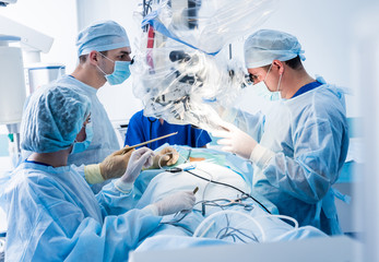 Spinal surgery. Group of surgeons in operating room with surgery equipment. Laminectomy
