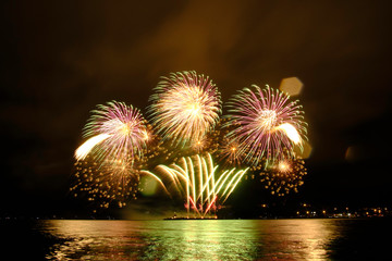 Beautiful colorful fireworks in sky over river. Big festive evening event with great pyrotechnic show.  