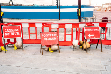 Worn out signs telling pedestrians the footpath and crossing are closed because of a construction...