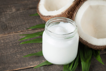 Ripe half cut coconut with green leaves on a wooden background.