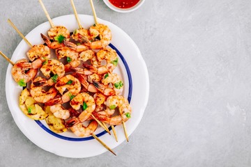 Sweet Chili Shrimp Skewers with lemon and parsley on gray stone background