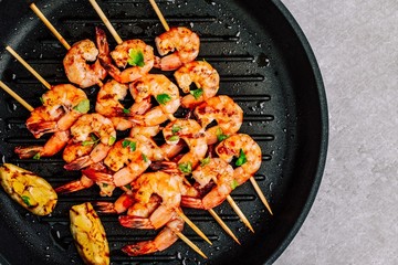 Sweet Chili Shrimp Skewers with lemon and parsley on gray stone background