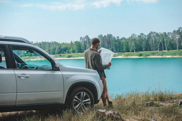 car travel concept man looking on the man at suv car hood lake on background
