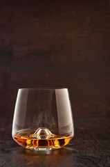 A crystal glass of whiskey on a wooden table.
