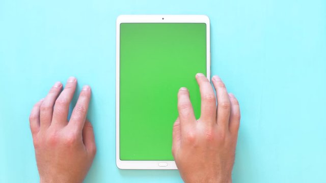 Male hand gesture enlarges the image on the tablet. 4k top view green screen footage.