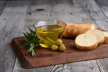glass bowl of olive oil with green olives and fresh bread