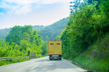 Yellow truck on the that goes through a beautiful countryside