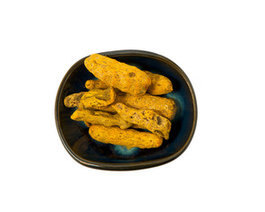 Dried turmeric root in a bowl isolated on a white background. Seasoning on isolate. View from above.