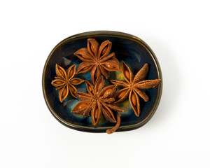 Anise in a bowl isolated on a white background. Seasoning on isolate. View from above. Close up view of anise stars.