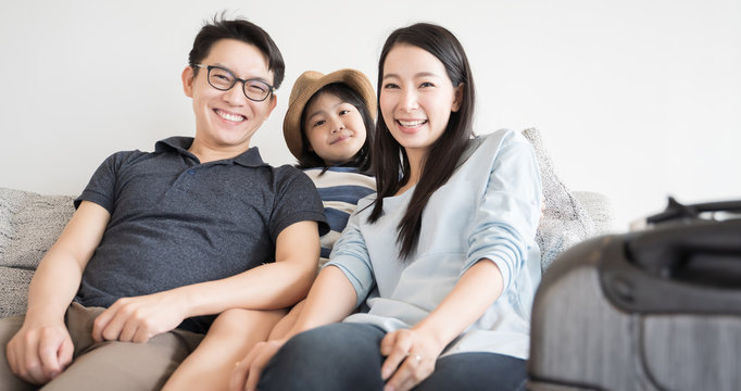 Portrait Asian Family With Luggage On Sofa In Living Room. Family Home And Travel Concept